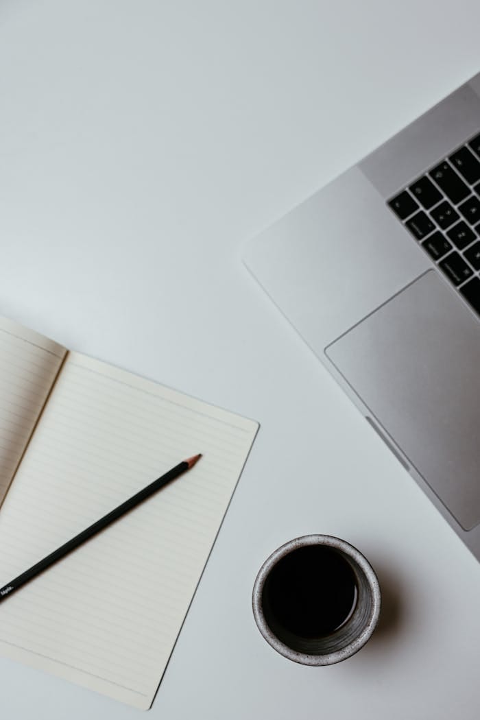 services-02 A clean, minimalist desk setup featuring a laptop, notebook, and coffee cup for productive work.