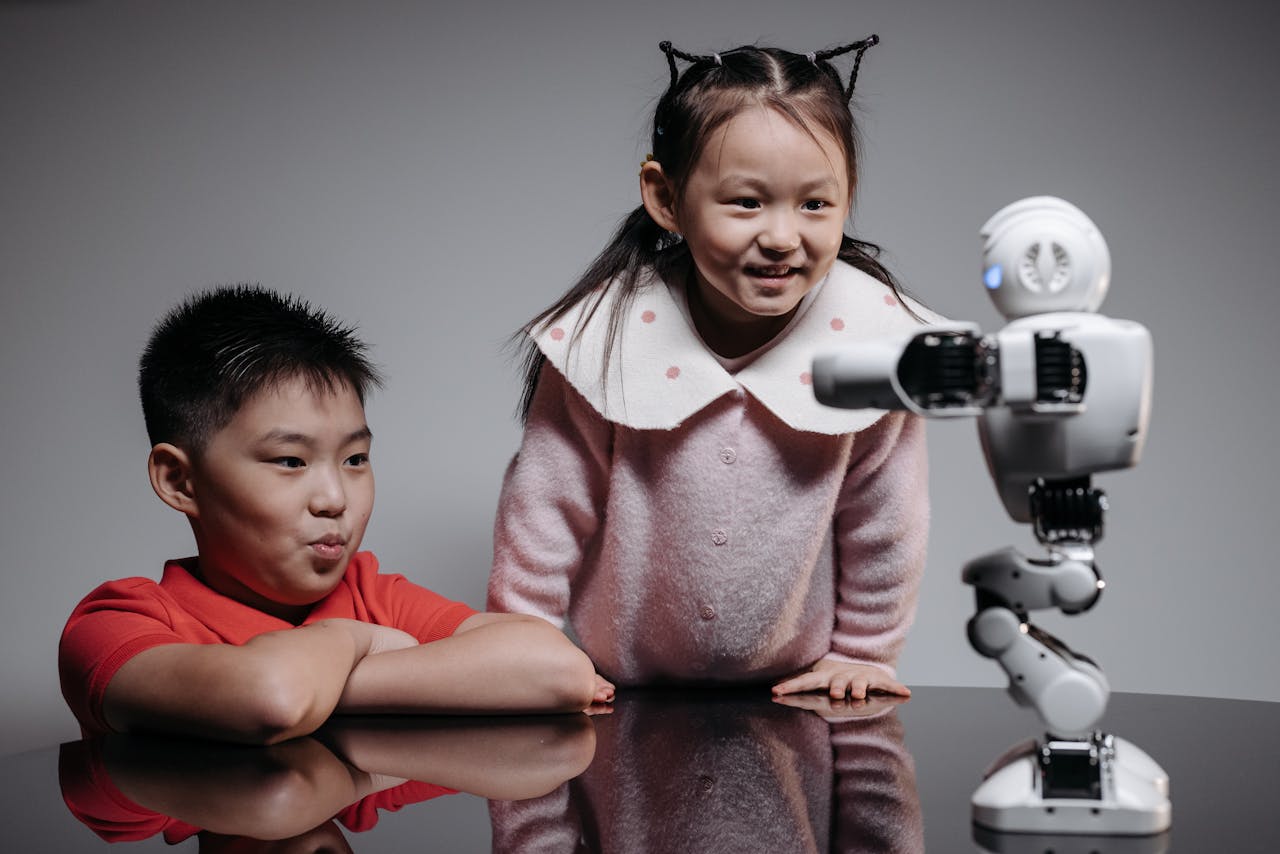 Two children interacting with a small robot, showcasing innovation and technology in a playful setting.